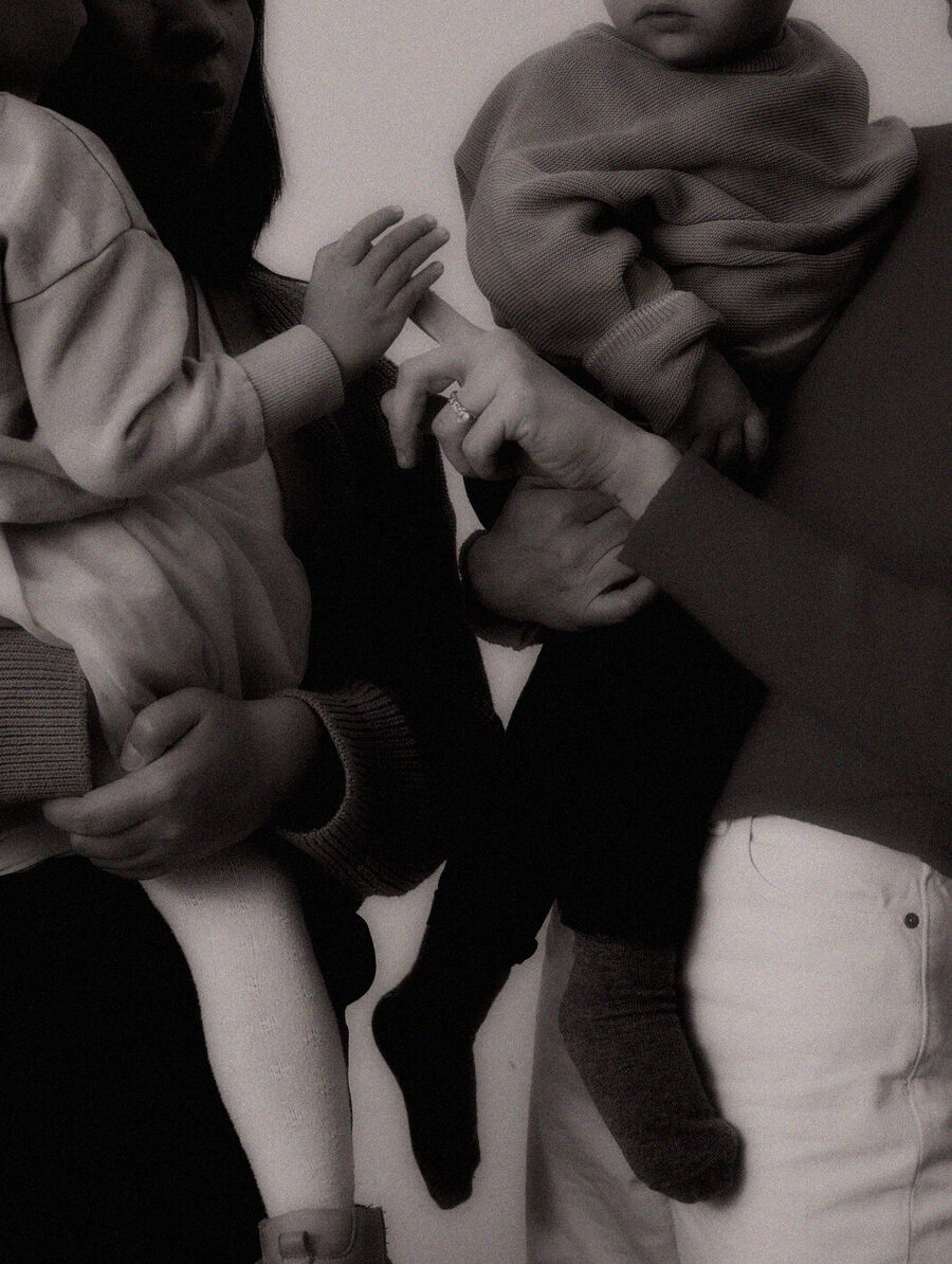 Two mothers standing close together, each holding a small child.
